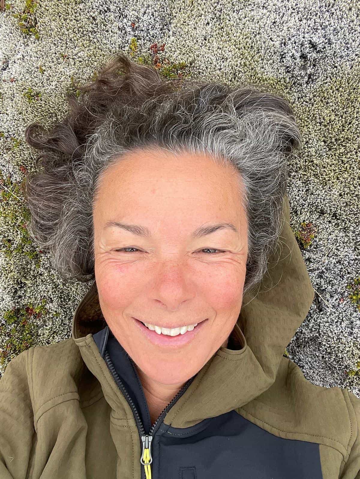 Caroline Tuchscherer sourit, allongée dans la mousse lors d'une sortie en nature.